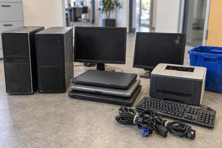 Oude laptops, desktops, monitoren, een printer en kabels.