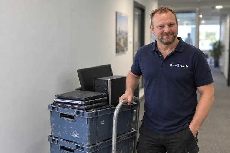 Bob naast een steekwagen met oude laptops en computers.